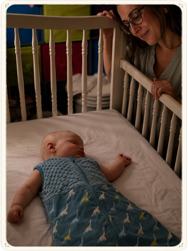 A peaceful baby sleeping while mom looks into the crib